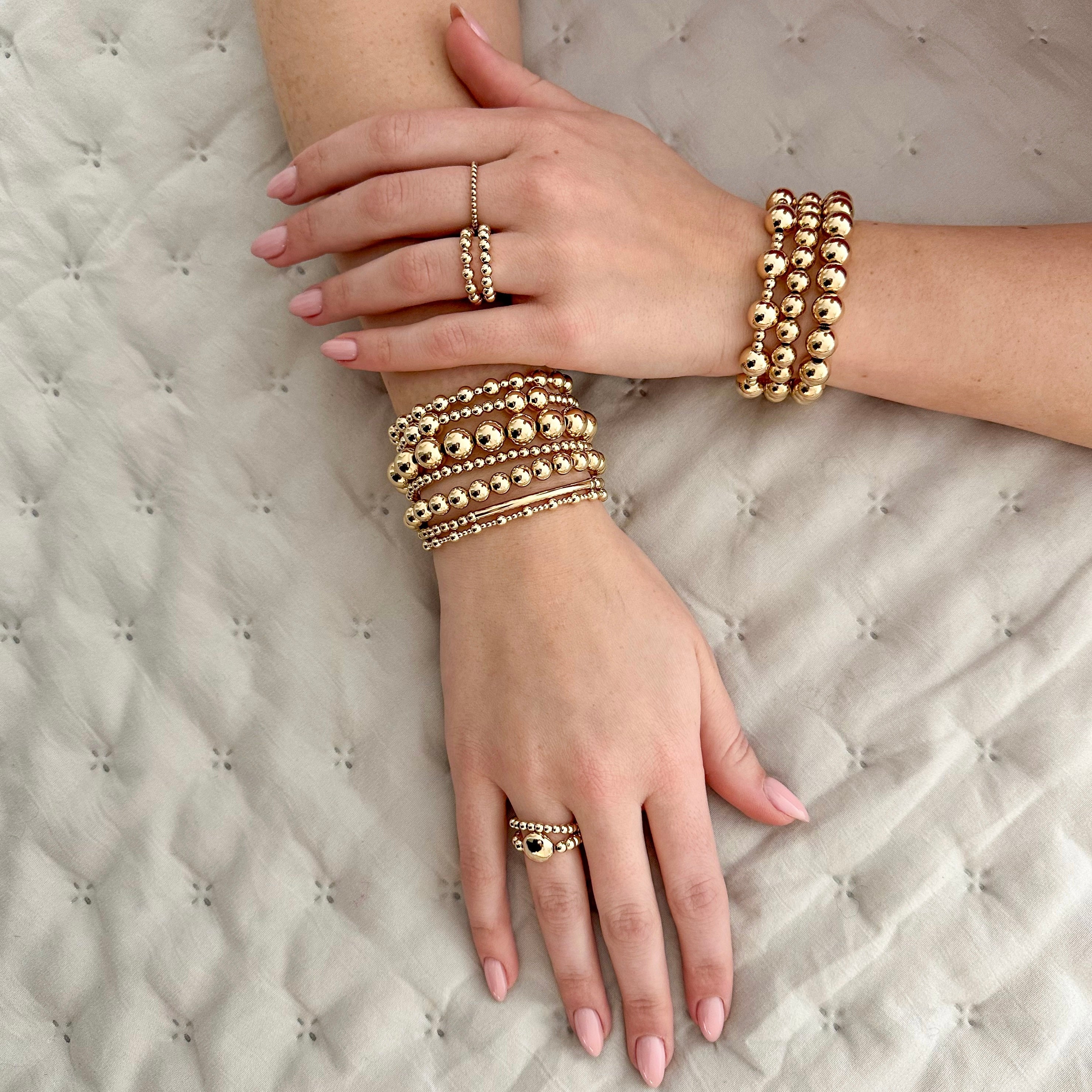 Foto van handen met gouden armbanden en ringen